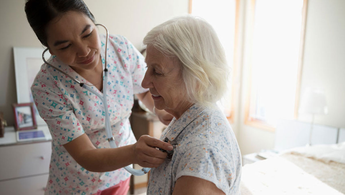 Filipino female nurse caring for retired person