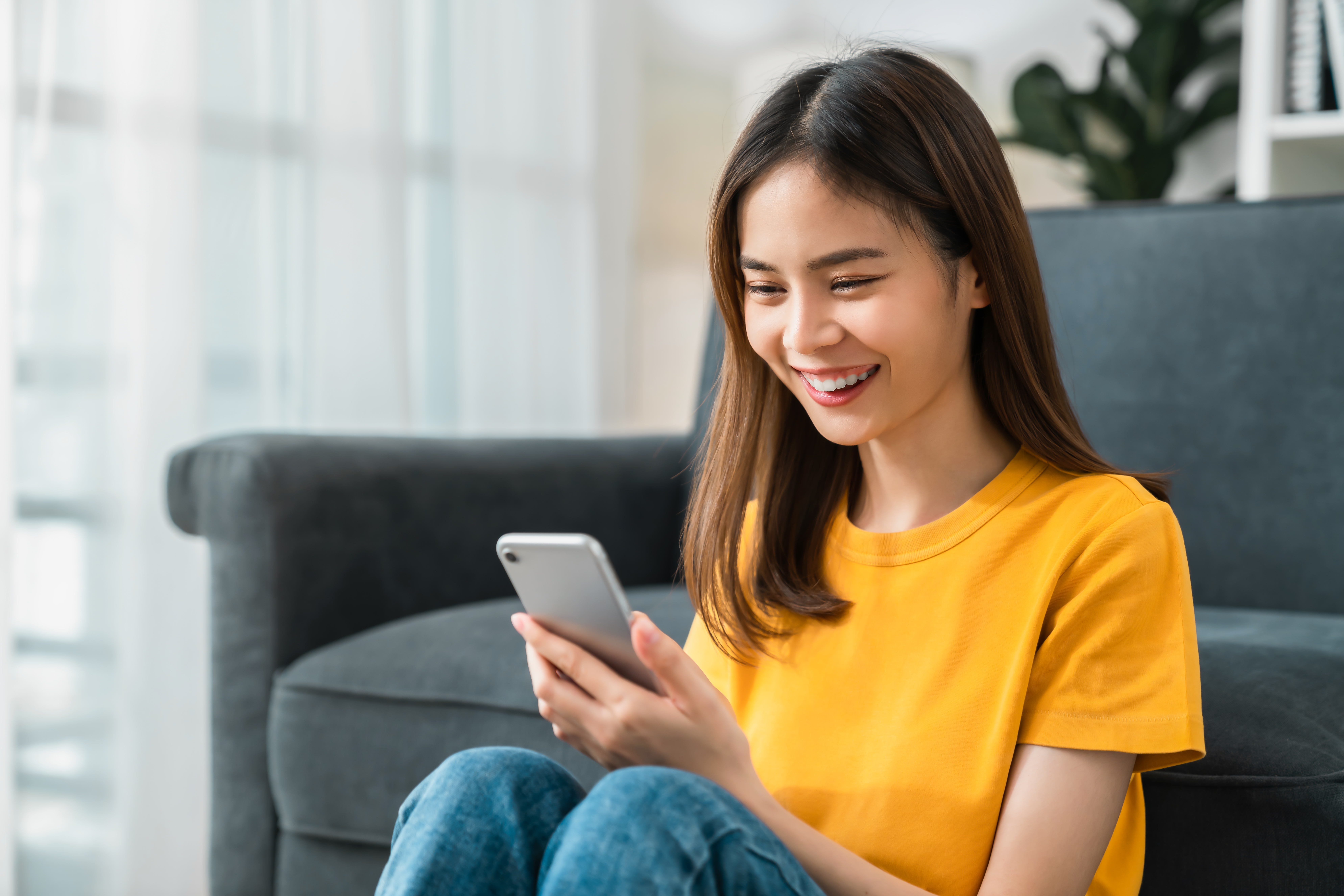 smiling young woman using phone relaxing at home 2026 01 06 10 53 42 utc
