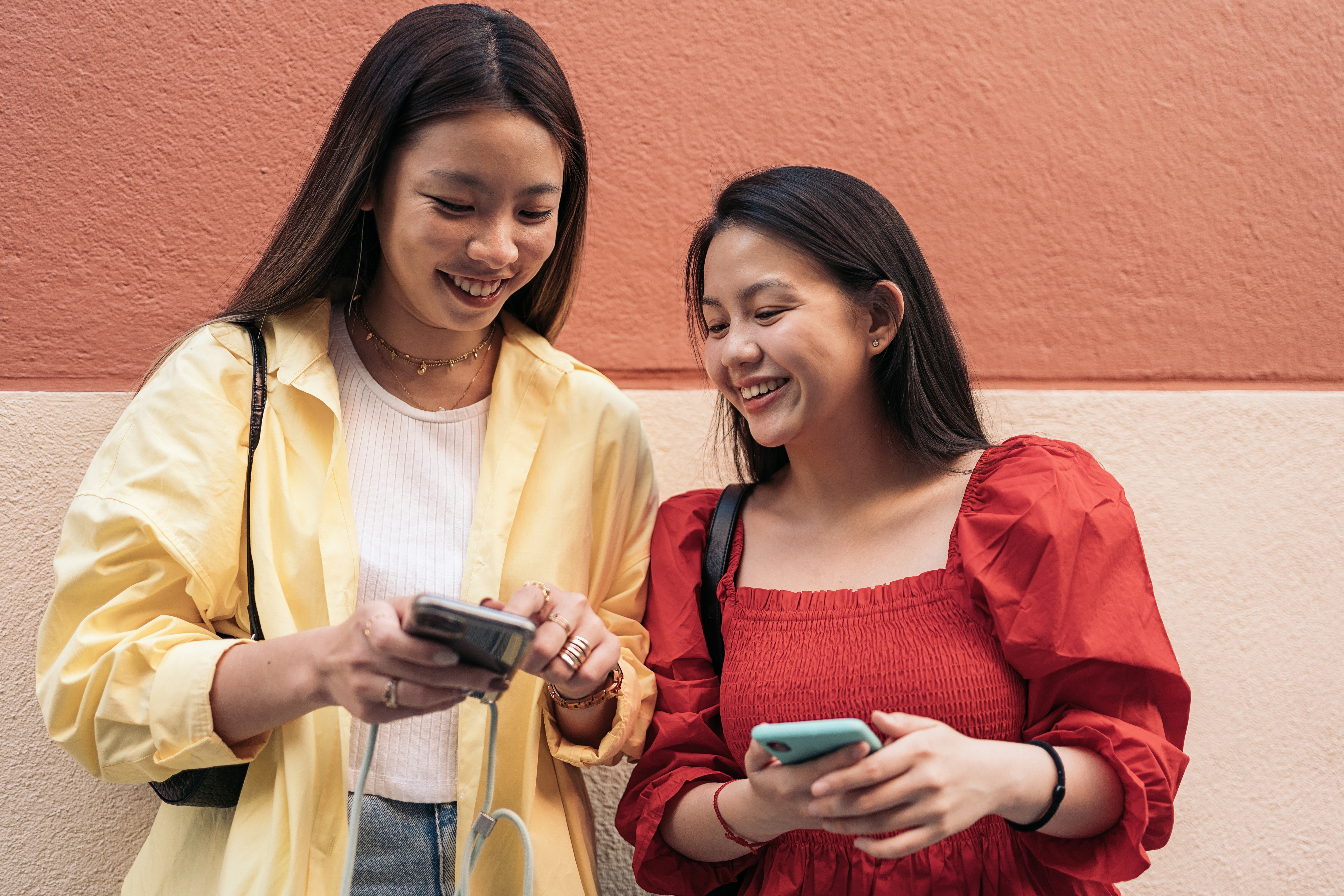 two young women smiling and holding cell phones 2026 09 22 17 20 07 utc